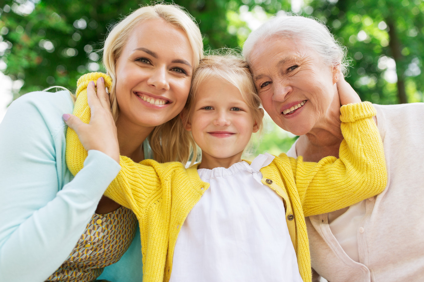 Junges Mädchen umarmt Mutter und Oma mit beiden Armen