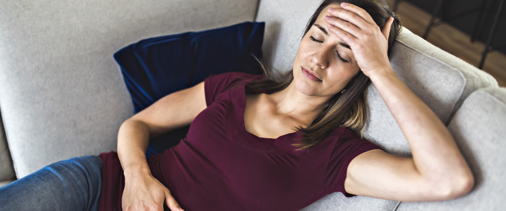 Frau liegt leidend auf dem Sofa