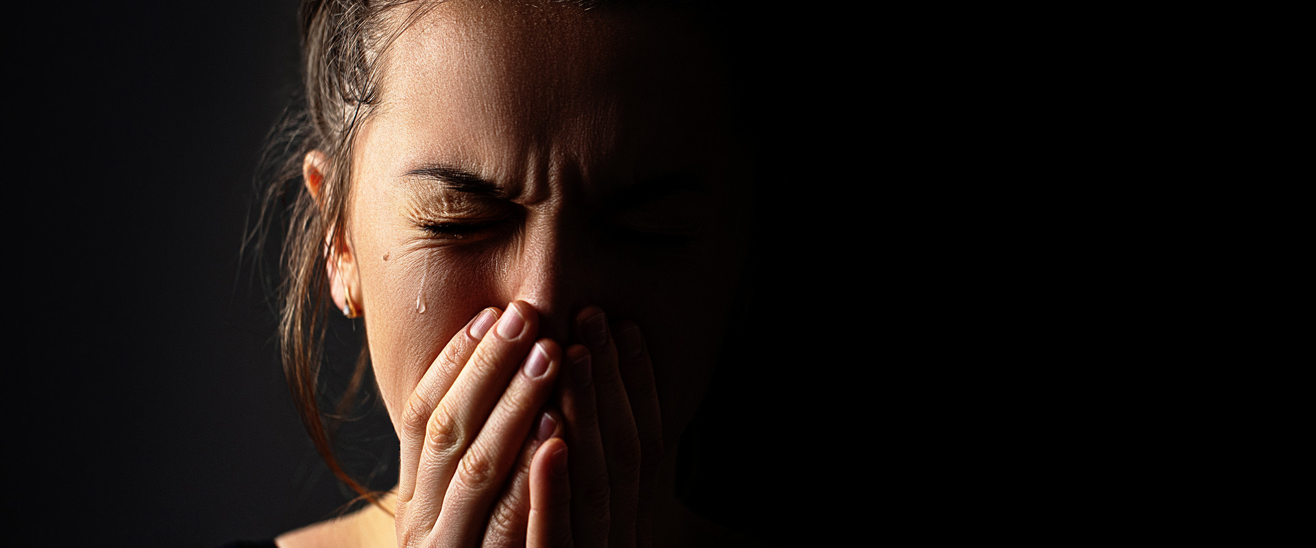 Weinende Frau vor dunklem Hintergrund