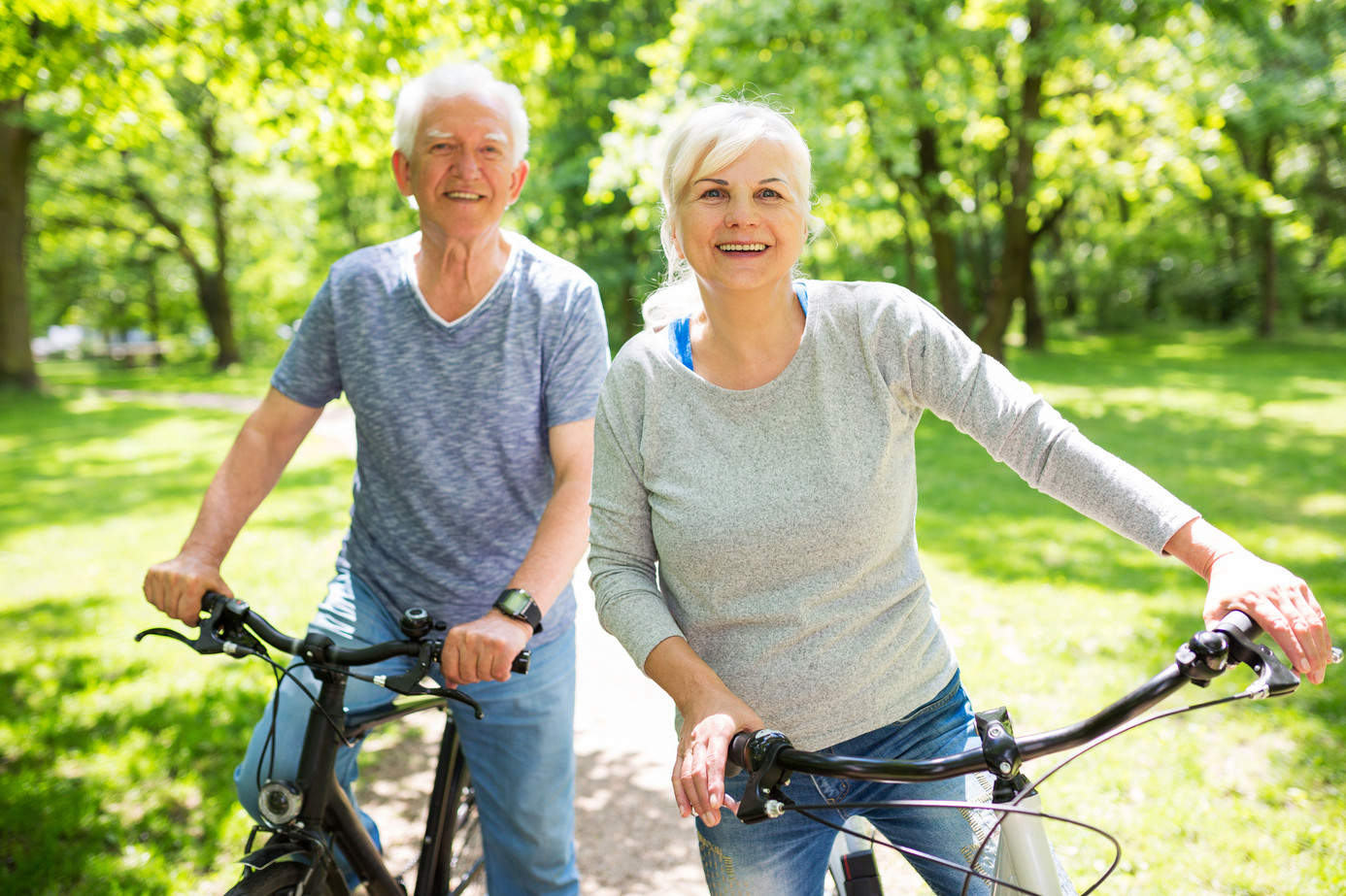 Fröhliches älteres Paar auf Fahrrädern im Wald