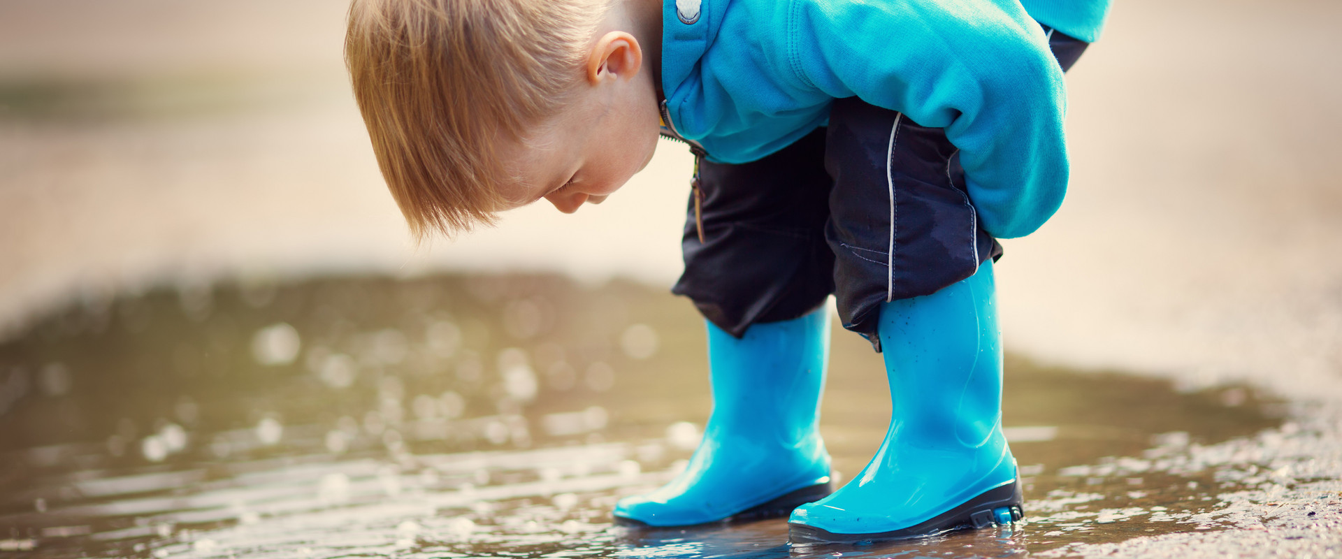 Kind mit Gummistiefel in Pfütze